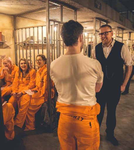 Warden interacting with prisoners in the cells at Alcotraz - prison-themed immersive cocktail bar experience.