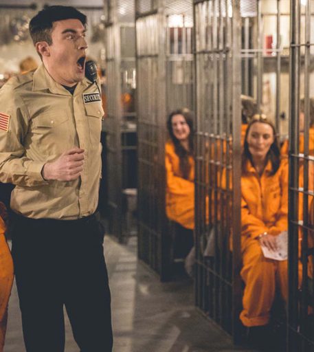 Prison guard character with customers at Alcotraz - interactive staff enhancing the immersive cocktail bar experience.