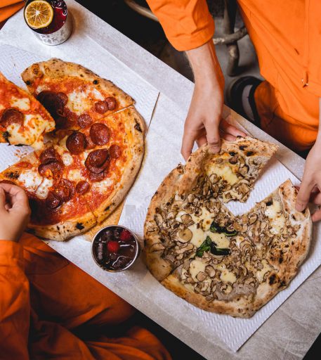Food service at Alcotraz immersive prison bar - pizza with custom cocktails for a complete night out experience.