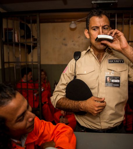 Prison guard character interacting with inmates at Alcotraz Brighton location - immersive prison-themed cocktail bar.