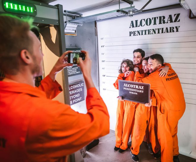 Inmates taking mugshot at Alcotraz Shoreditch interior - prison-themed immersive cocktail bar.