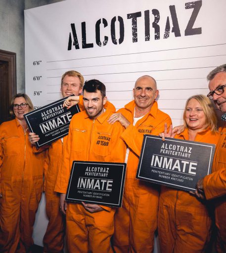 Inmates taking family mug shot at Alcotraz - immersive prison bar experience for fun nights out.