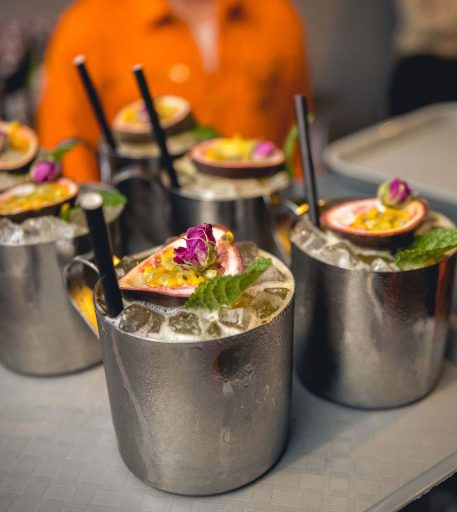 Tray of custom canteen cocktails with fruit garnish at Alcotraz - immersive prison bar experience for nights out.
