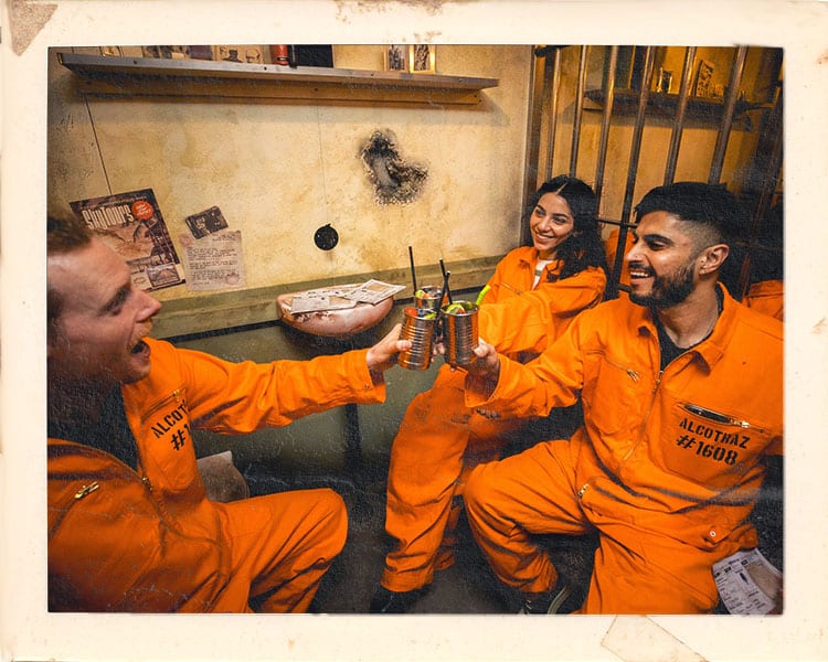 Inmates drinking in Alcotraz prison cells - prison-themed immersive cocktail bar for fun nights out.