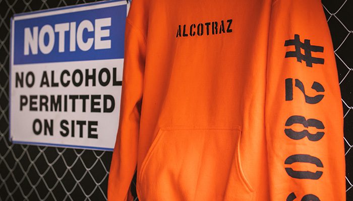 Alcotraz prison-themed merchandise - orange inmate hoodie souvenir from the immersive cocktail bar experience.