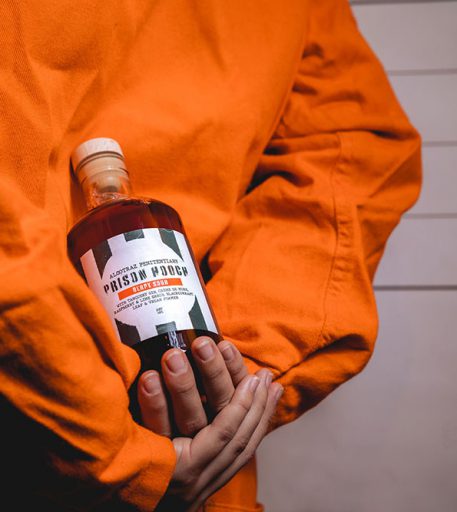 Prisoner character holding prison hooch cocktails at Alcotraz - specialty drinks in immersive prison bar experience.