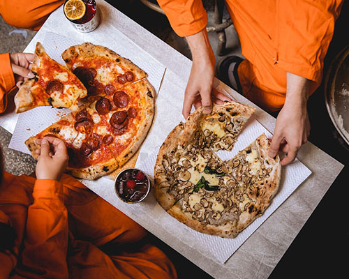 Food service at Alcotraz immersive prison bar - pizza with custom cocktails for a complete night out experience.