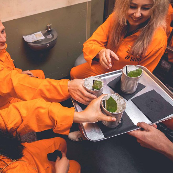 Inmates enjoying cocktails in prison cells at Alcotraz - immersive prison bar experience for group activities and hen nights.