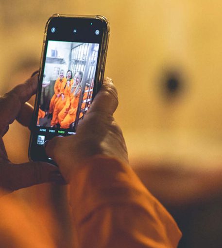 Customer taking photos of inmates in orange jumpsuits at Alcotraz - the interactive prison themed cocktail bar.