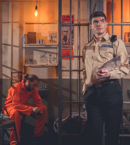 Prison warden character guarding inmate in the cells at Alcotraz Manchester - interactive prison-themed cocktail bar.