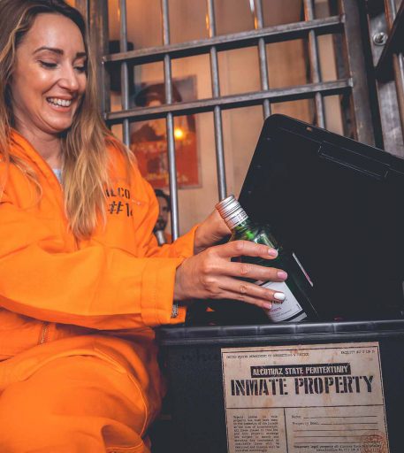 Inmate in orange jumpsuit at Alcotraz prison-themed bar - popular immersive experience for hen nights and celebrations.