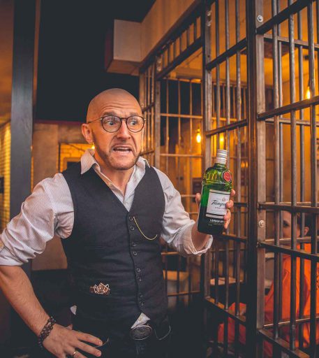 Prison officer character at Alcotraz - immersive bar experience - showing alcohol contraband to customers.