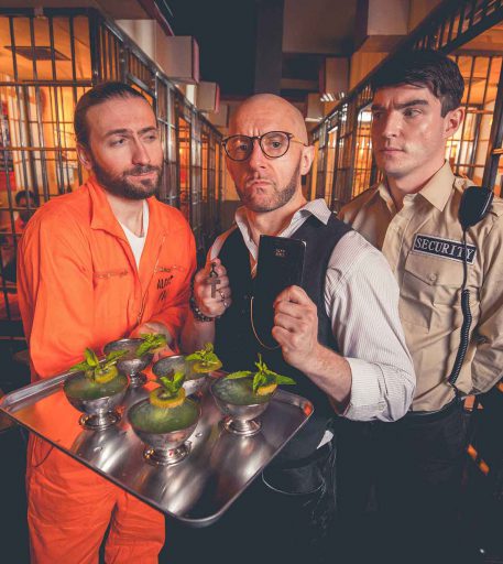 Inmates being served cocktails at Alcotraz - interactive experience at this prison-themed immersive bar.
