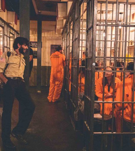 Friends enjoying custom cocktails at Alcotraz - prison-themed immersive bar perfect for group activities.