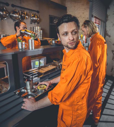 Prisoner character serving drinks at the canteen at Alcotraz - immersive experience at unique prison themed cocktail bar.