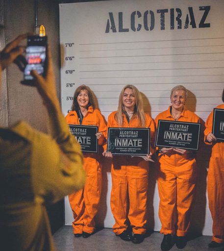 Prisoners in orange jumpsuits taking mug shots at Alcotraz - key part of immersive prison themed cocktail bar.