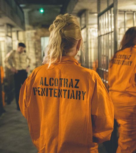 Inmate customers wearing orange jumpsuits at Alcotraz - interactive prison themed cocktail bar for fun nights out.