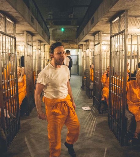 Prison cell block at Alcotraz immersive experience with inmate customers enjoying the interactive bar experience.