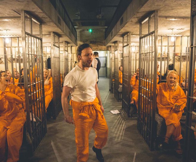 Prison cell block at Alcotraz immersive experience with inmate customers enjoying the interactive bar experience.