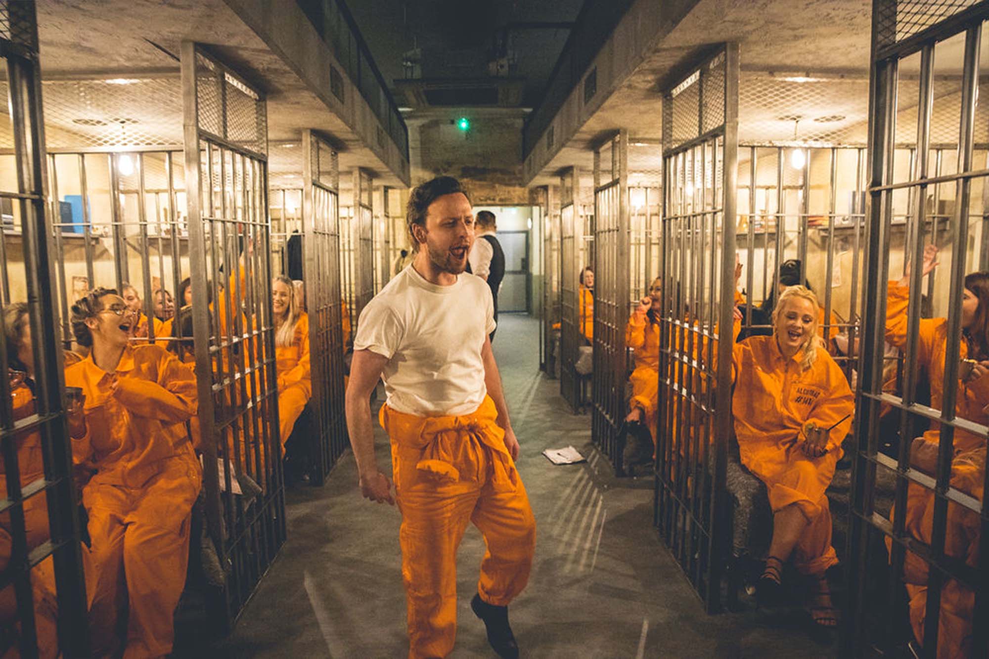 Prison cell block at Alcotraz immersive experience with inmate customers enjoying the interactive bar experience.