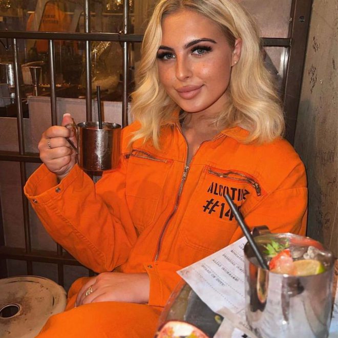 Custom cocktail being served to customer in orange jumpsuit at Alcotraz - immersive prison bar experience.