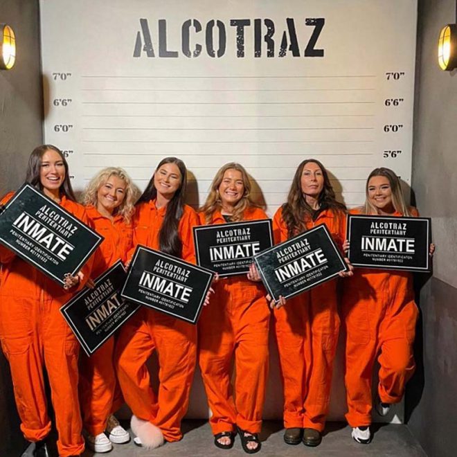 Friends taking mug shot at Alcotraz - key part of immersive cocktail bar in prison setting.