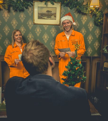 Customers in orange jumpsuits enjoying Christmas cocktails at this immersive prison bar experience for festive celebrations