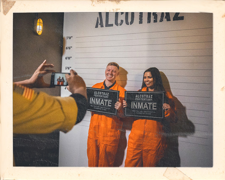 Couple taking mug shot photos during date night at Alcotraz - interactive element of this immersive prison bar experience.