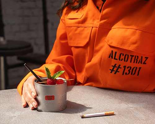 Inmate with unique cocktail at Alcotraz - immersive prison cocktail bar experience.